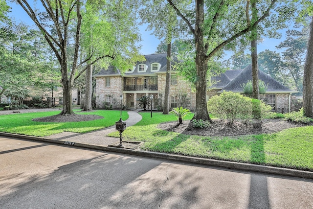 french country inspired facade with a front lawn and stone siding