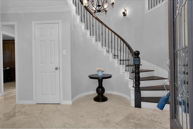 staircase with an inviting chandelier, baseboards, and crown molding