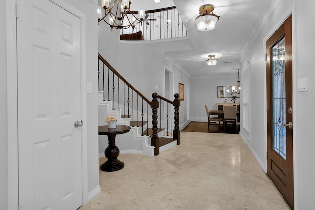 foyer entrance with an inviting chandelier, baseboards, ornamental molding, and stairs