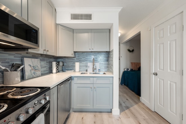 kitchen with visible vents, decorative backsplash, ornamental molding, a sink, and stainless steel appliances