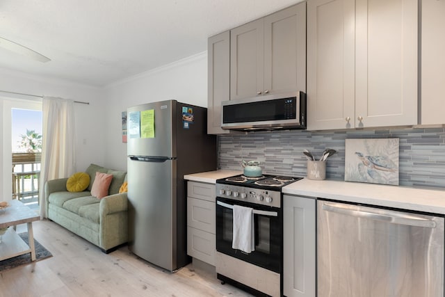 kitchen with crown molding, light wood-style floors, light countertops, stainless steel appliances, and tasteful backsplash