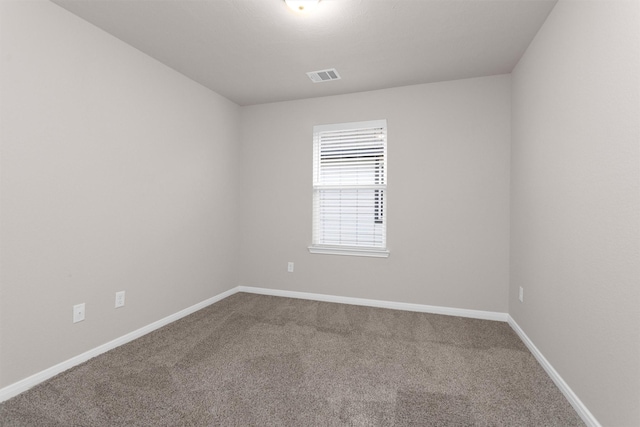 spare room featuring baseboards, visible vents, and carpet
