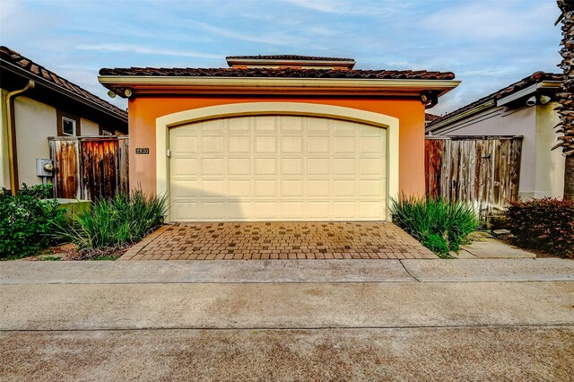 garage with decorative driveway and fence