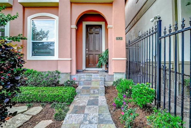 property entrance with fence and stucco siding