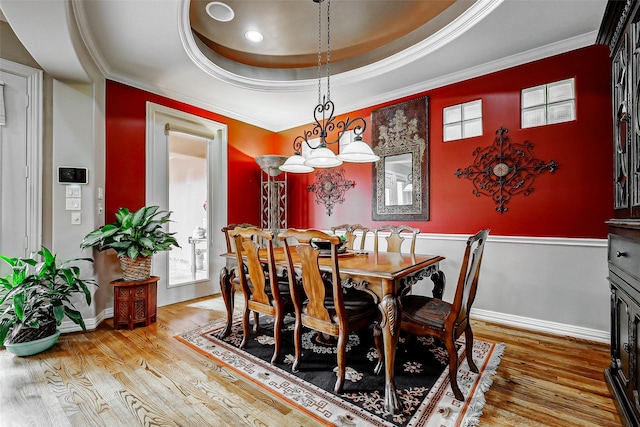 dining area featuring baseboards, ornamental molding, a raised ceiling, and wood finished floors