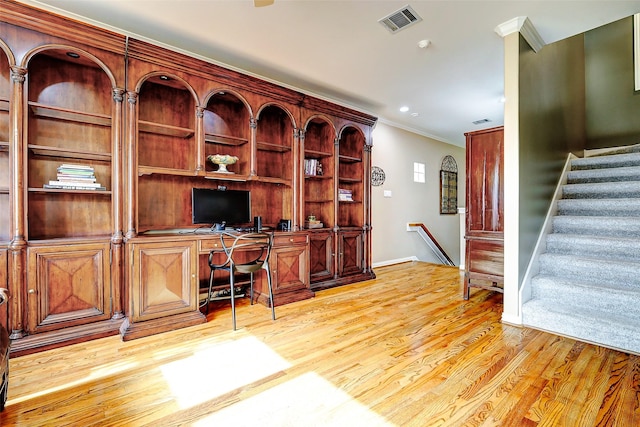 office area with visible vents, crown molding, light wood-type flooring, built in desk, and baseboards