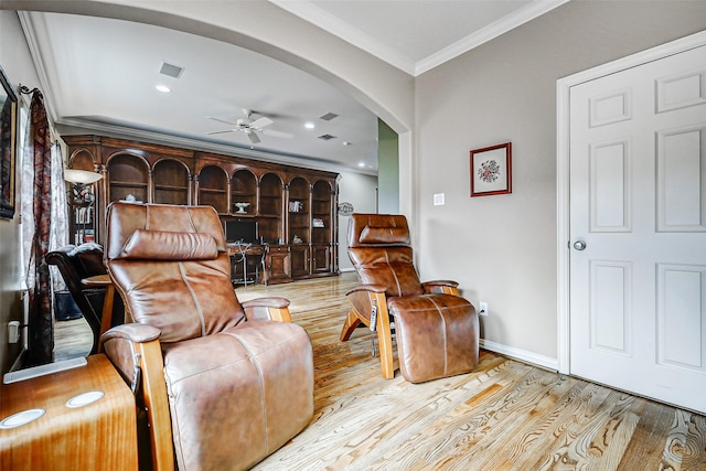 living room with crown molding, a ceiling fan, visible vents, wood finished floors, and arched walkways
