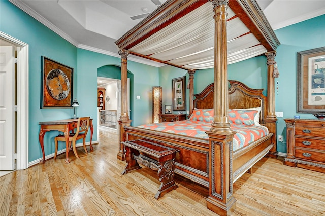 bedroom featuring crown molding, arched walkways, baseboards, and wood finished floors