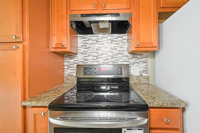 3045 Walnut Bend Ln Unit 27, Houston, TX 77042 - kitchen featuring wall chimney range hood, decorative backsplash, light stone countertops, stainless steel range with electric cooktop, and freestanding refrigerator
