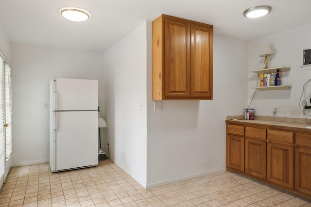 6625 E Post Rd, Kyle, TX 78640 - kitchen featuring light countertops, baseboards, freestanding refrigerator, and brown cabinetry