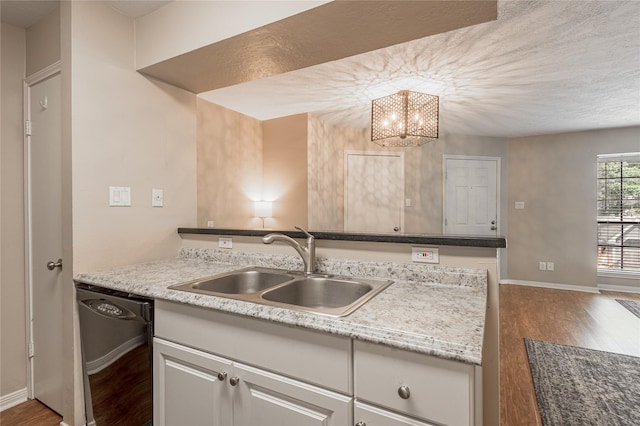 kitchen with dark wood-style flooring, dishwasher, a sink, baseboards, and an inviting chandelier