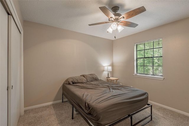 carpeted bedroom featuring baseboards, ceiling fan, a closet, and a textured ceiling
