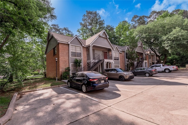 bungalow-style house with stairway, uncovered parking, and brick siding