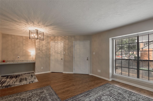 foyer featuring baseboards, a textured ceiling, wood finished floors, and a notable chandelier