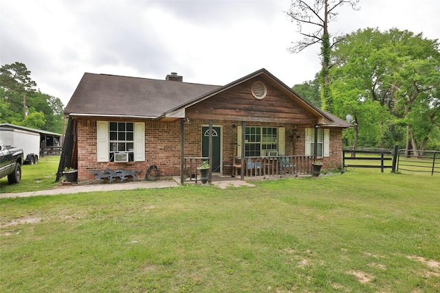 view of front of property featuring brick siding, fence, a chimney, and a front lawn