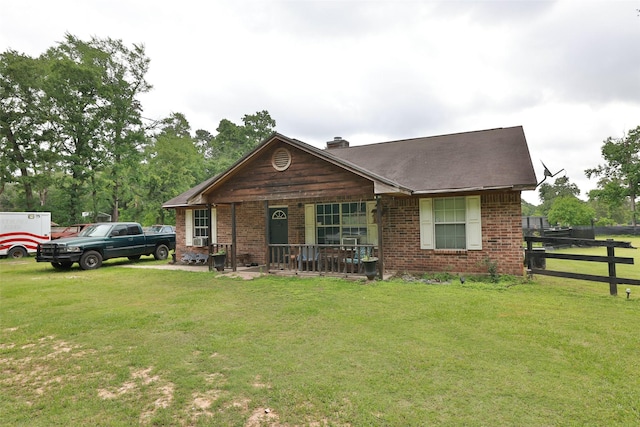view of front of property featuring a front lawn, fence, covered porch, and a chimney