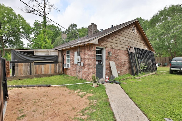 view of home's exterior with brick siding, a lawn, fence, and a chimney