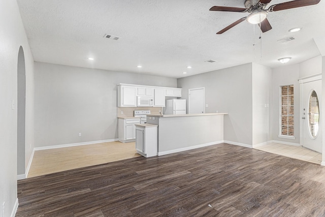 unfurnished living room with ceiling fan, light wood finished floors, a textured ceiling, and visible vents