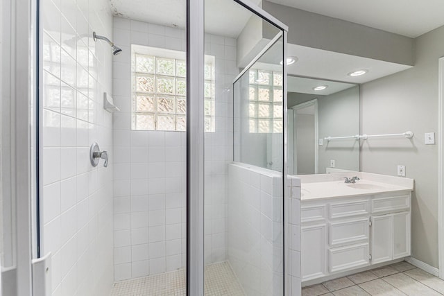 full bath featuring a shower stall, vanity, tile patterned floors, baseboards, and recessed lighting