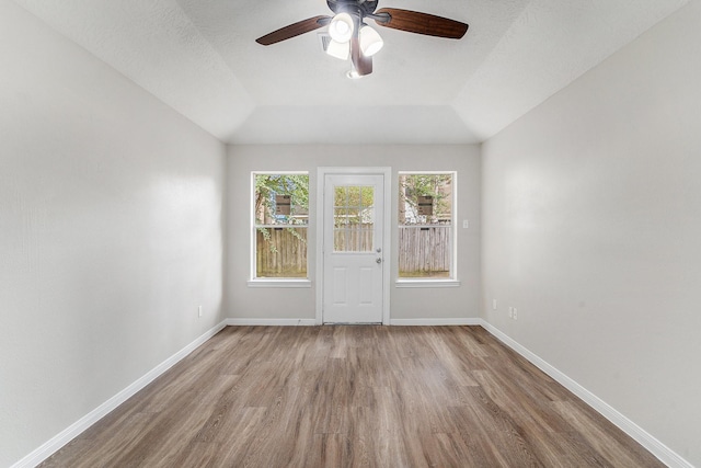 spare room with baseboards, a ceiling fan, wood finished floors, and lofted ceiling