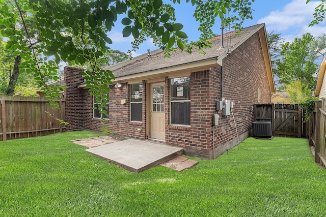 rear view of house with a lawn, central air condition unit, brick siding, a fenced backyard, and a patio