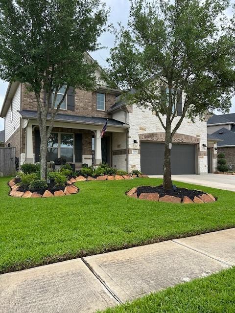 15419 Greenford Glen Dr, Cypress, TX 77429 - view of front of home with stone siding, concrete driveway, fence, and a front yard