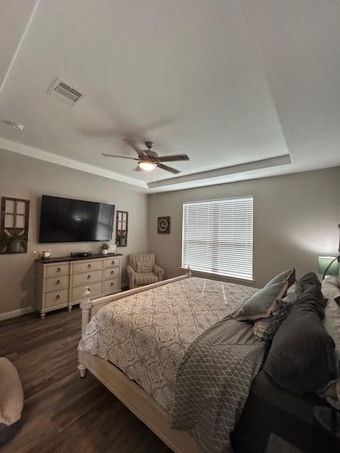15419 Greenford Glen Dr, Cypress, TX 77429 - bedroom with a tray ceiling, baseboards, ceiling fan, visible vents, and dark wood-type flooring