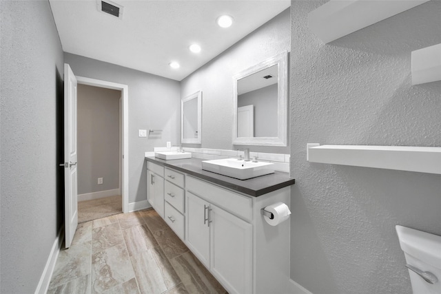1226 Westgreen Blvd, Katy, TX 77450 - bathroom featuring visible vents, double vanity, a textured wall, toilet, and a sink