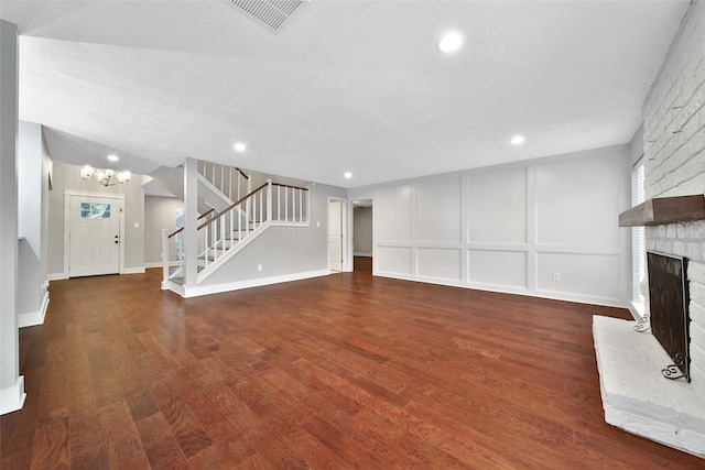 1226 Westgreen Blvd, Katy, TX 77450 - unfurnished living room with visible vents, a large fireplace, wood finished floors, a notable chandelier, and stairs