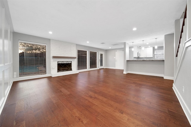 1226 Westgreen Blvd, Katy, TX 77450 - unfurnished living room with recessed lighting, baseboards, a brick fireplace, and dark wood-style floors