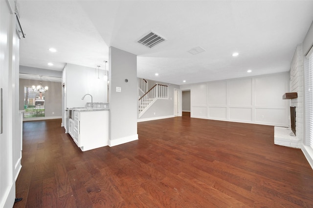 1226 Westgreen Blvd, Katy, TX 77450 - interior space with a notable chandelier, a brick fireplace, dark wood-type flooring, visible vents, and stairway