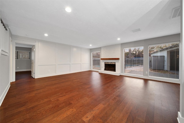 1226 Westgreen Blvd, Katy, TX 77450 - unfurnished living room featuring visible vents, a fireplace, dark wood finished floors, a decorative wall, and recessed lighting
