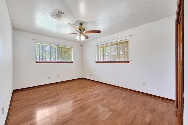 spare room with a ceiling fan, baseboards, visible vents, and light wood finished floors