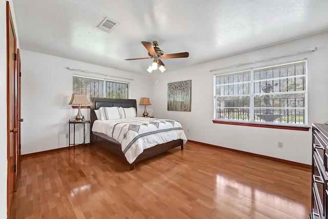 bedroom with baseboards, ceiling fan, wood finished floors, and visible vents