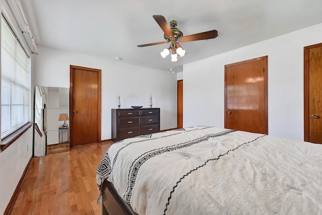 bedroom featuring baseboards, light wood finished floors, and ceiling fan