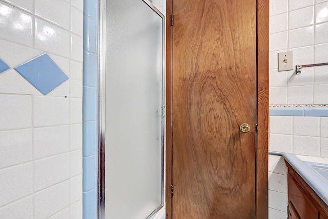 bathroom featuring vanity, tile walls, and a shower with door