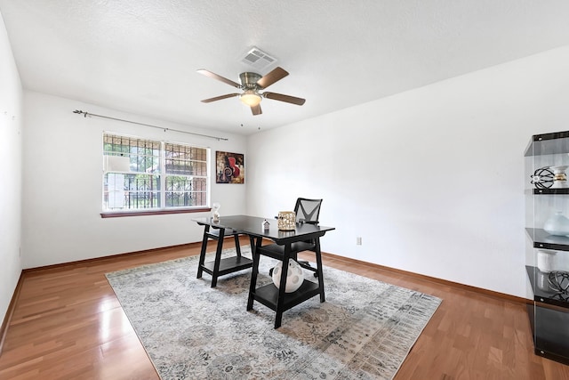 office space with baseboards, ceiling fan, visible vents, and wood finished floors