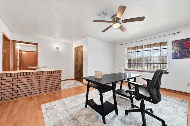 home office with a ceiling fan, baseboards, visible vents, and light wood-style floors