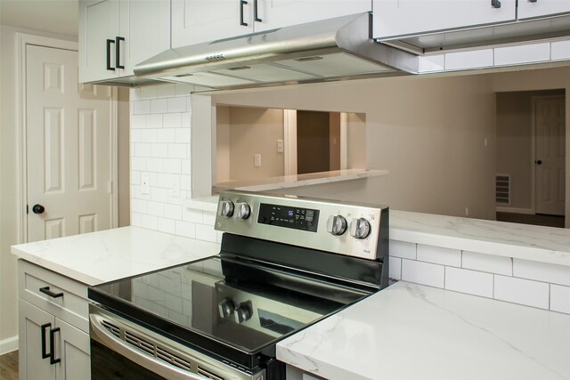 1222 Lynn Ln, Humble, TX 77338 - kitchen with light stone counters, decorative backsplash, under cabinet range hood, and electric stove