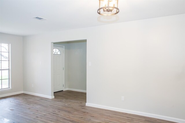 1222 Lynn Ln, Humble, TX 77338 - empty room featuring visible vents, baseboards, wood finished floors, and a notable chandelier