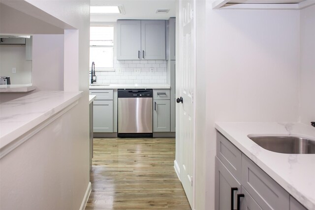 1222 Lynn Ln, Humble, TX 77338 - kitchen with tasteful backsplash, light wood-type flooring, dishwasher, gray cabinetry, and a sink