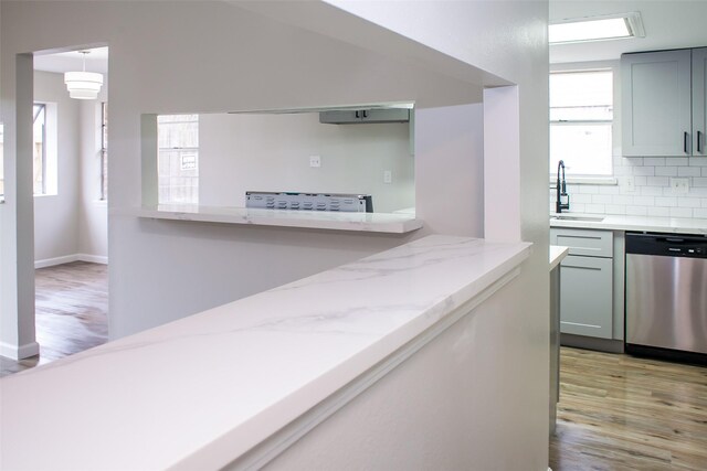 1222 Lynn Ln, Humble, TX 77338 - kitchen with a sink, decorative backsplash, stainless steel dishwasher, and light wood finished floors