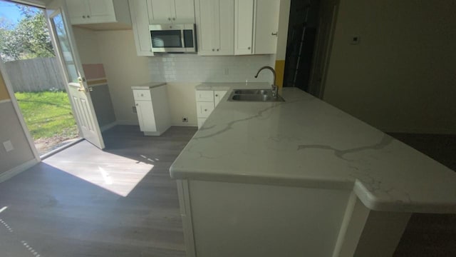 kitchen with stainless steel microwave, light stone counters, a healthy amount of sunlight, and a sink