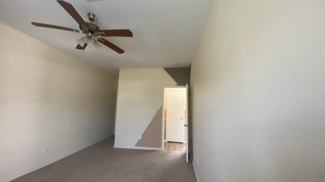 carpeted spare room with baseboards and a ceiling fan
