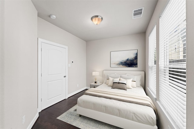 bedroom featuring baseboards, wood finished floors, and visible vents
