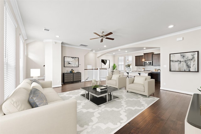 living area featuring visible vents, ornamental molding, and dark wood-type flooring