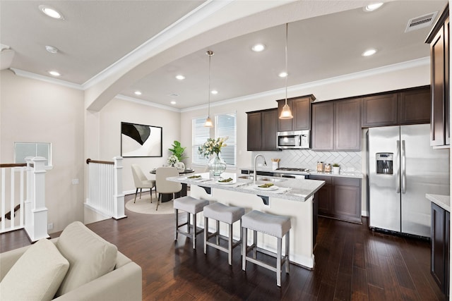 kitchen featuring visible vents, crown molding, a kitchen bar, a sink, and appliances with stainless steel finishes