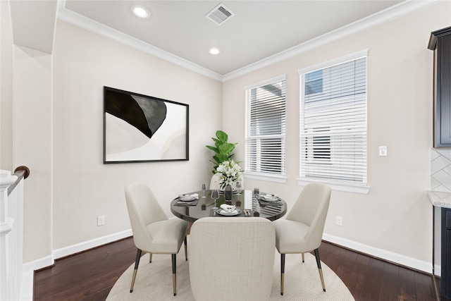 dining area featuring baseboards, visible vents, ornamental molding, and wood finished floors