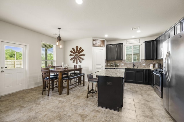 kitchen featuring appliances with stainless steel finishes, dark cabinets, backsplash, a kitchen island, and visible vents
