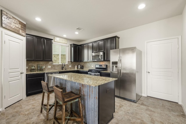 kitchen with backsplash, visible vents, a center island, light stone countertops, and stainless steel appliances